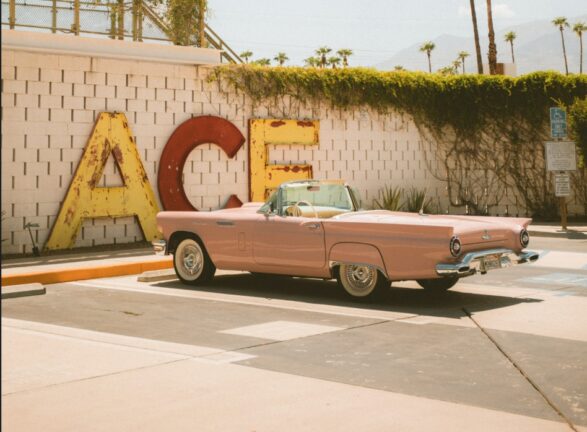 Pink vintage convertible parked in front of the ACE sign at Ace Hotel & Swim Club Palm Springs